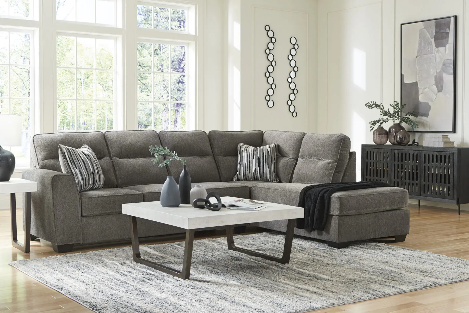 Benchcraft Olten Graphite 2-Piece Sectional with Chaise featuring plush charcoal gray upholstery, deep chaise lounge, and patterned throw pillows