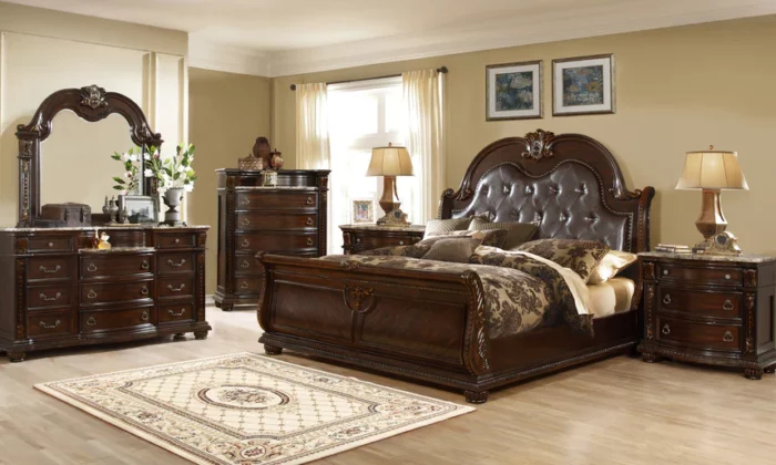 B9505 6 Piece Bedroom Set in deep mahogany finish, featuring a tufted leatherette headboard, intricate carvings, and real marble top on dresser and nightstands.